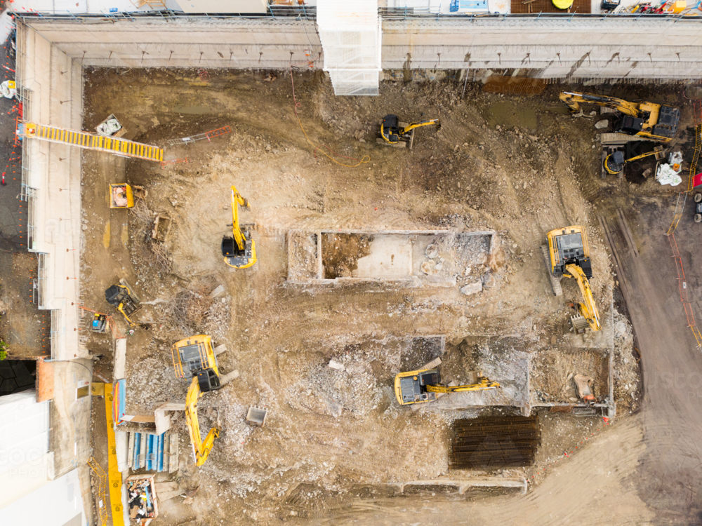 Aerial image above an excavated construction site with several machines in excavated pit - Australian Stock Image