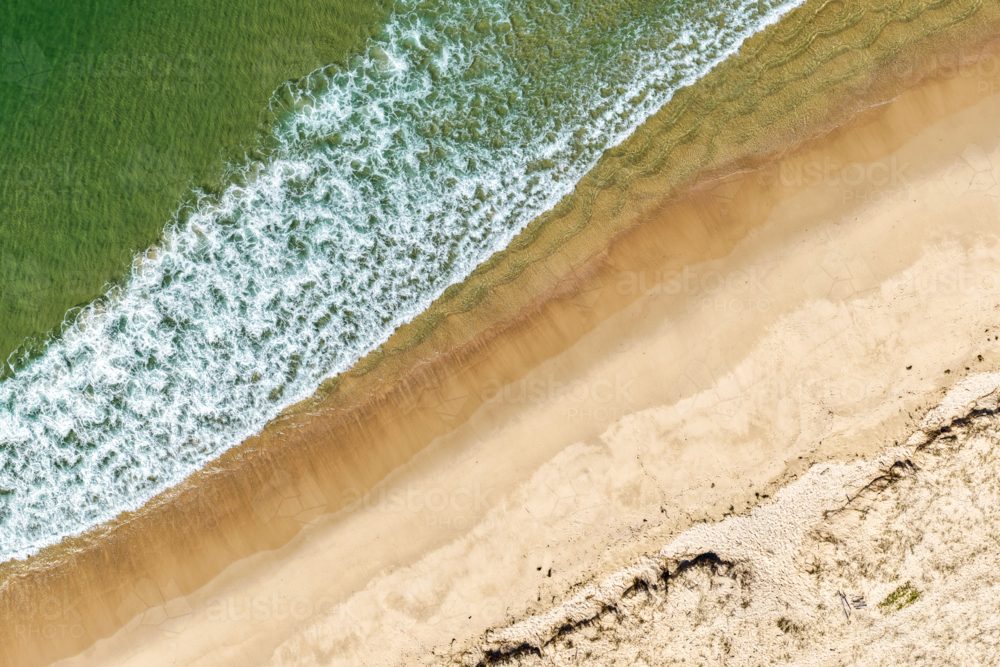 Aerial image capturing waves rolling onto the sandy shoreline of Nine Mile Beach in Tuncurry - Australian Stock Image