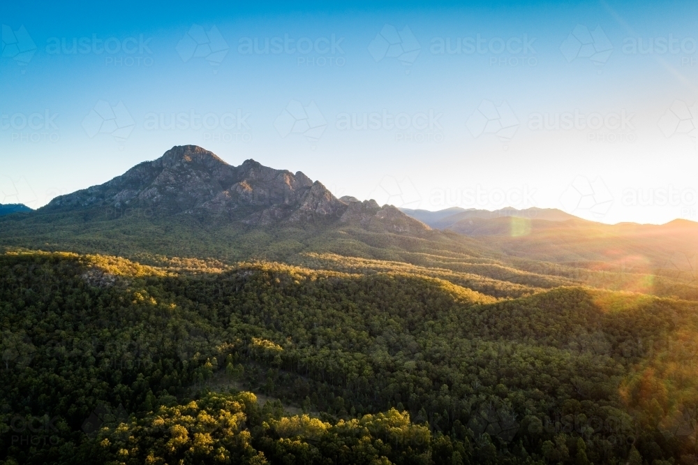 aerial landscape of a rocky mountain and forest at sunset - Australian Stock Image