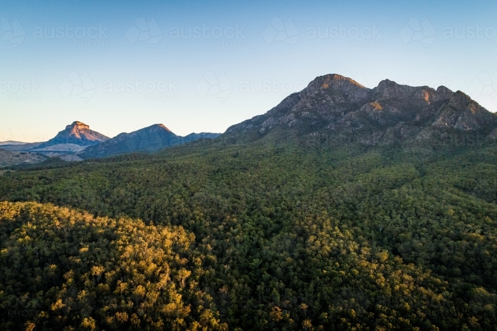 Aerial landscape of Rocky Mountains and forest at sunset - Australian Stock Image
