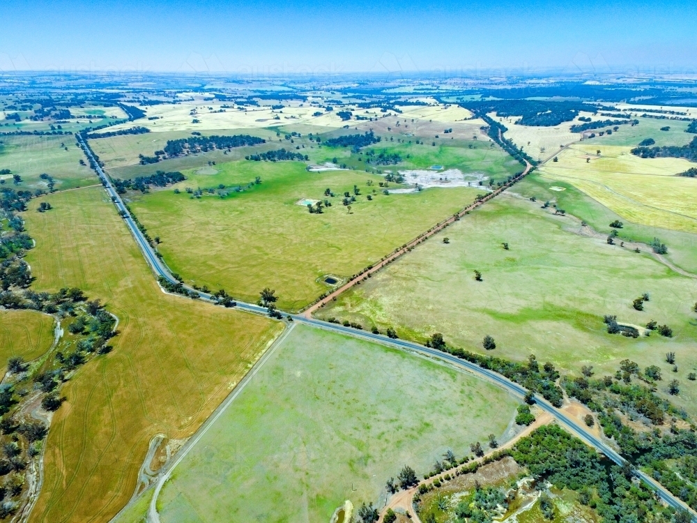 Aerial landscape over farming land with road cutting through - Australian Stock Image