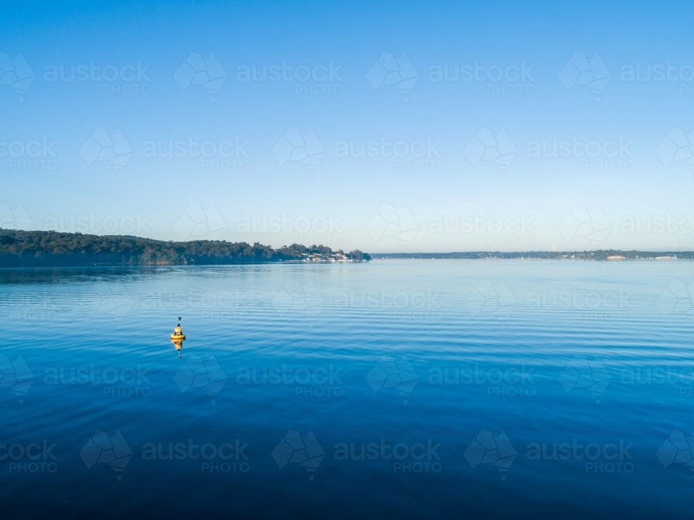 Aerial landscape view over blue water of lake Macquarie on calm morning - Australian Stock Image