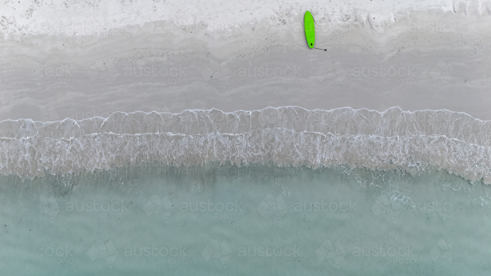 Aerial of a paddle board laying on the sand at the shoreline - Australian Stock Image