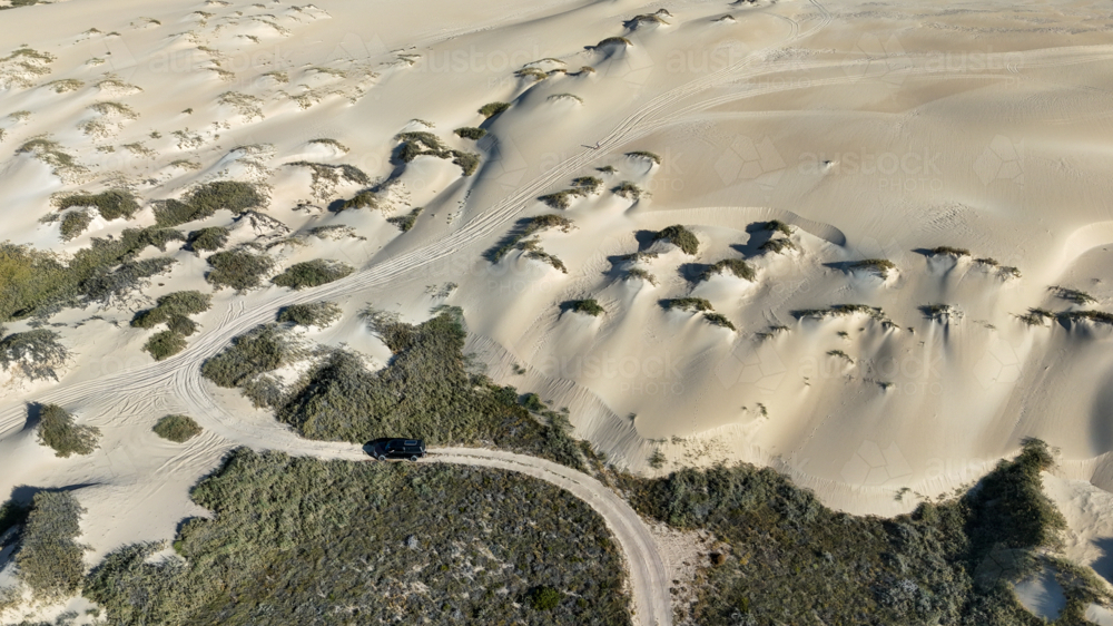 Aerial of car parked at bottom of sand dunes - Australian Stock Image