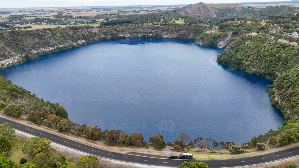 Aerial of caravan parked up next to big blue lake in a town - Australian Stock Image