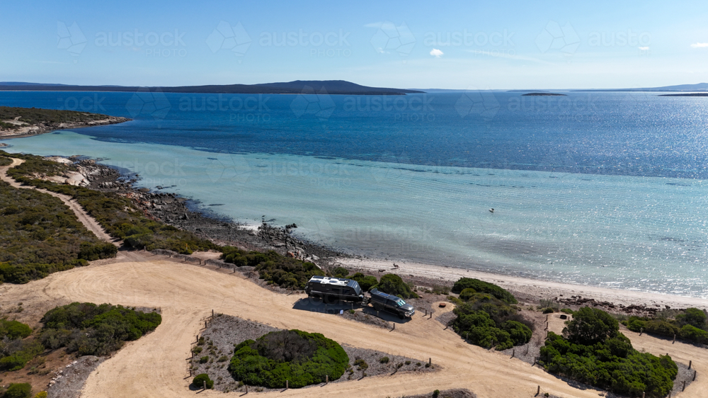 Aerial of caravan set up at campsite by a remote beach - Australian Stock Image