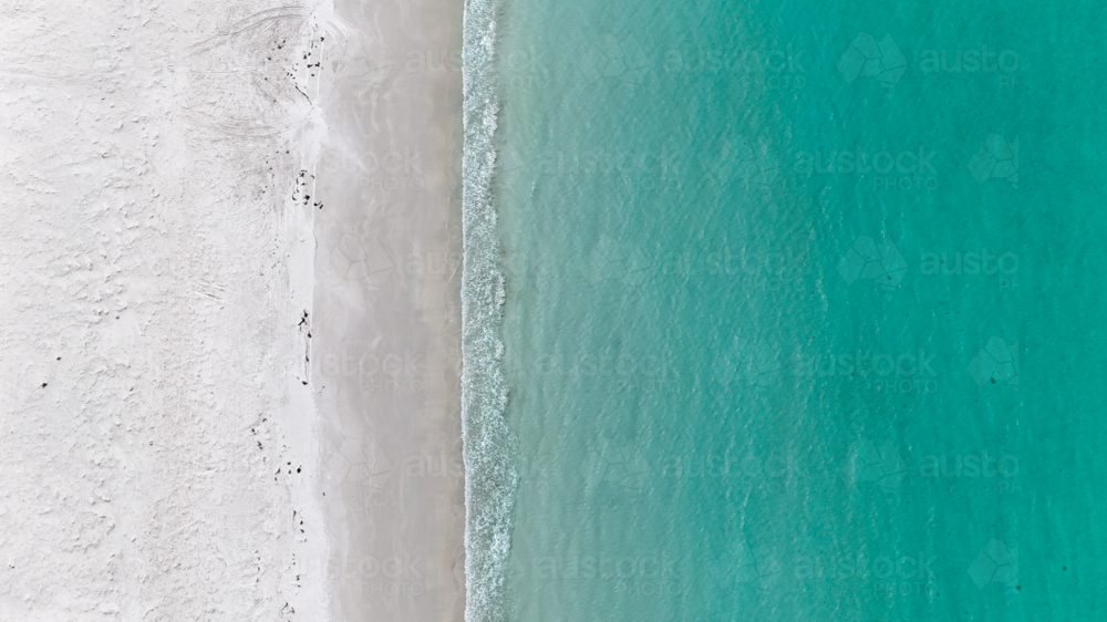 Aerial of clear blue water meeting white sand - Australian Stock Image