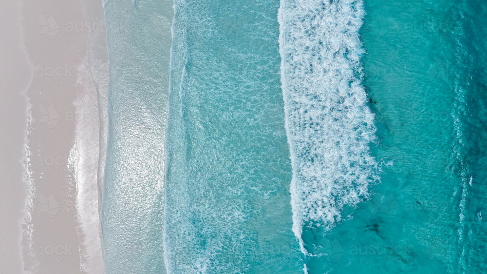Aerial of crystal blue waves crashing onto perfect white sand - Australian Stock Image