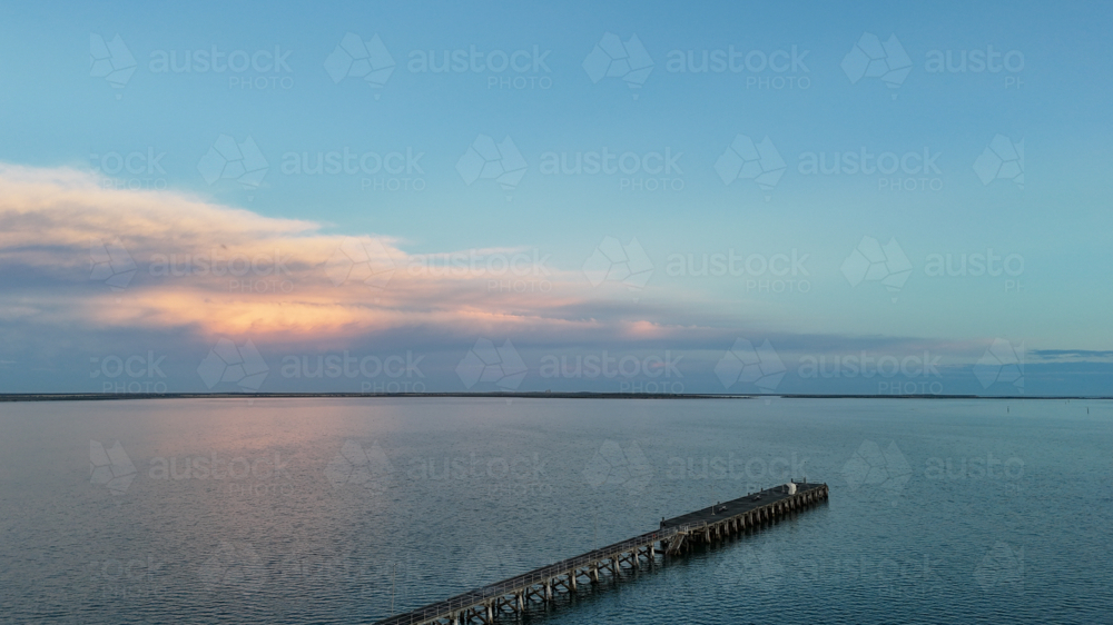 Aerial of jetty out on water at sunset - Australian Stock Image