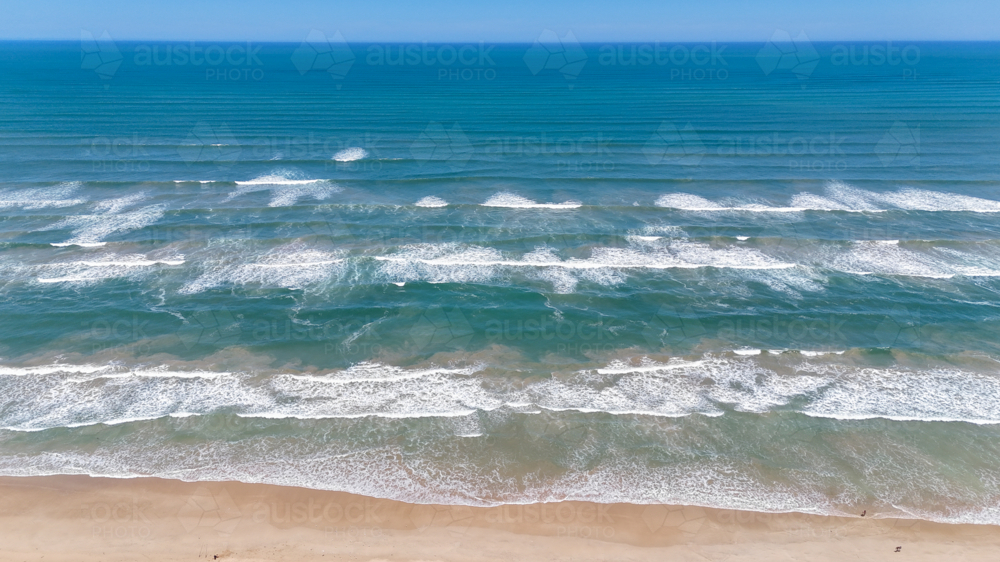 Aerial of multiple sets of waves on a remote beach - Australian Stock Image