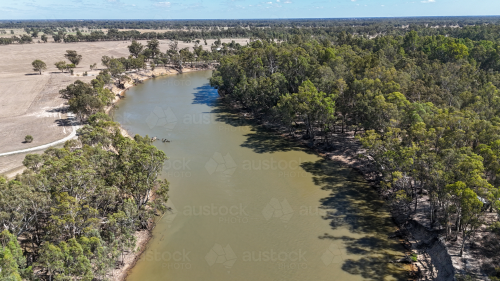 Aerial of Murray River bending through trees and rural land in dry season - Australian Stock Image