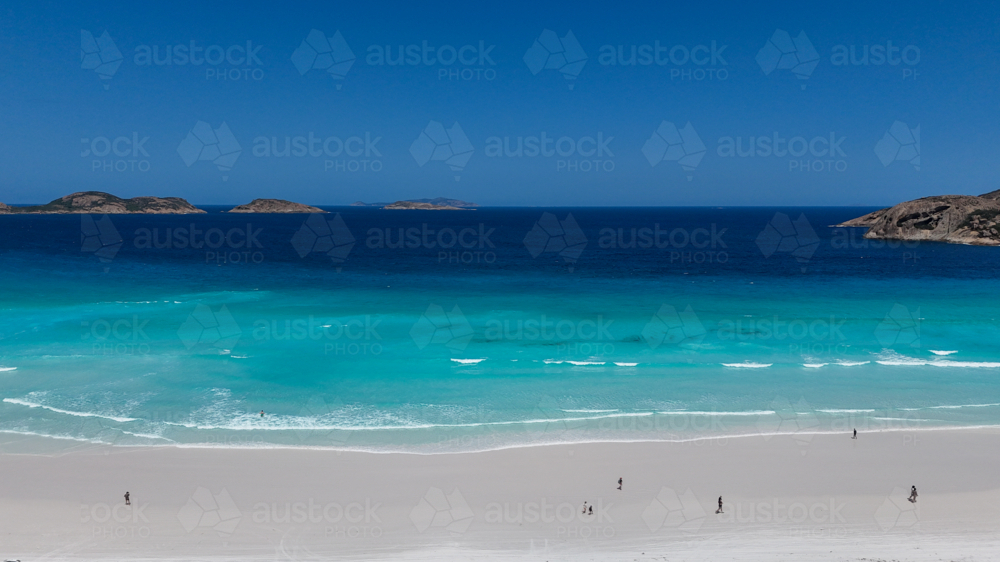 Aerial of people walking along beach either white sand and crystal blue water - Australian Stock Image