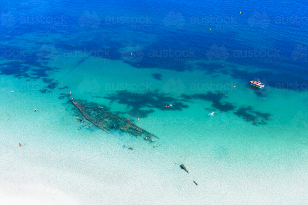 Aerial of shipwreck can be seen in the crystal clear ocean near local beach - Australian Stock Image