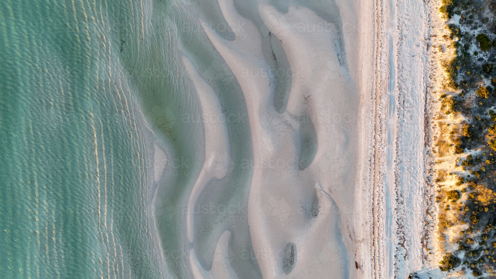 Aerial of the tide coming in at a beach at golden hour - Australian Stock Image