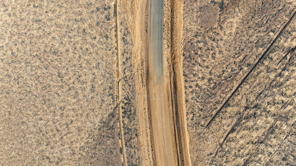 Aerial of where the dirt road meets the tar - sealed to unsealed road - Australian Stock Image