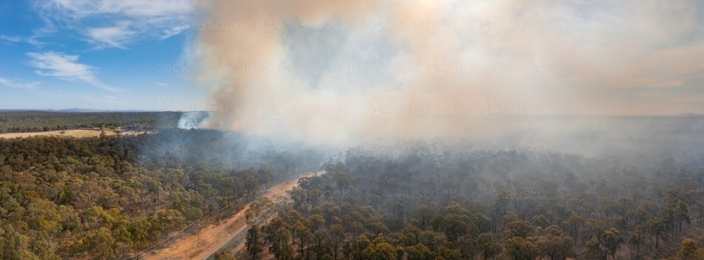 Aerial panorama of plumes of brown bushfire smoke rising from bushland - Australian Stock Image