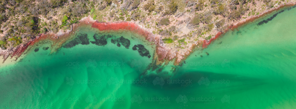 Aerial panorama view of a coastal river bank with rocks covered in colorful lichen - Australian Stock Image