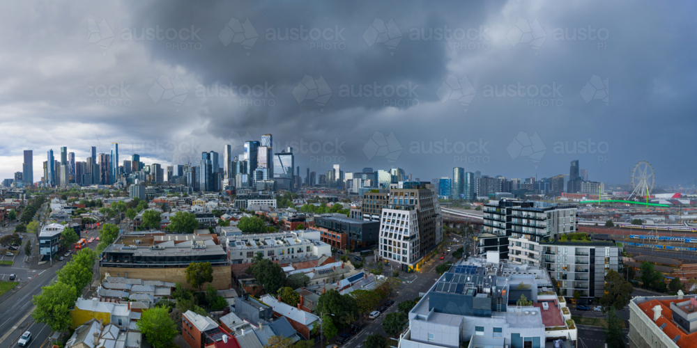 Aerial panorama view of dark storm clouds and rain moving over a distant city skyline - Australian Stock Image