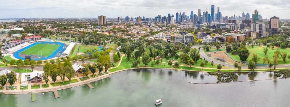 Aerial panoramic view of a sporting arena on the shores of a lake in front of a city skyline - Australian Stock Image