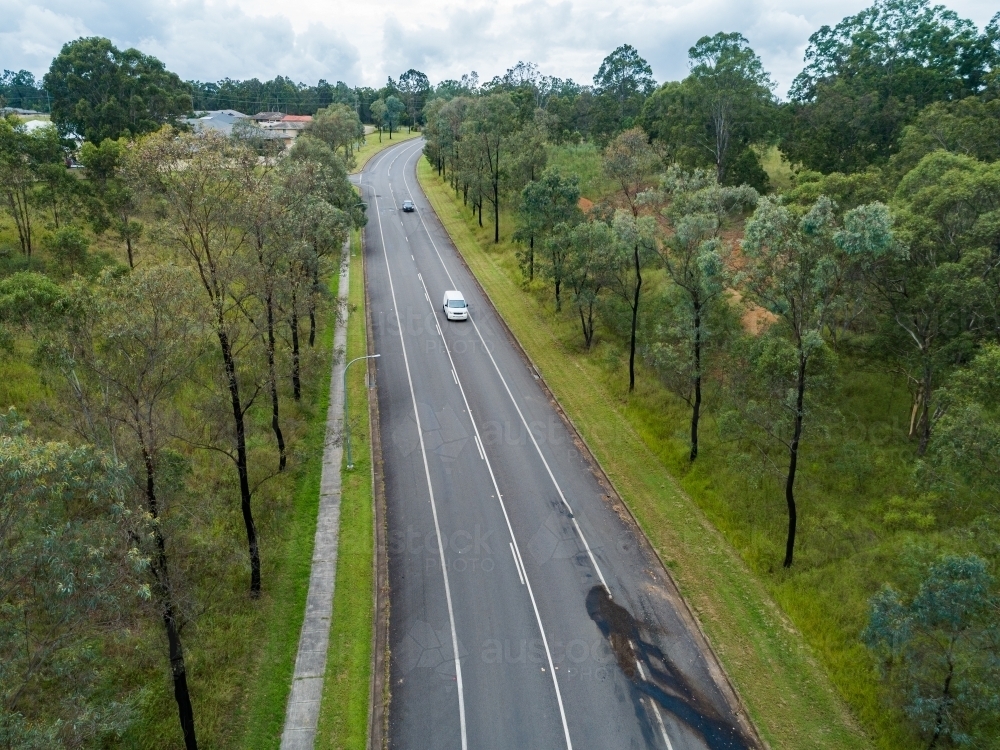 Aerial shot of footpath beside road leading up a hill - Australian Stock Image