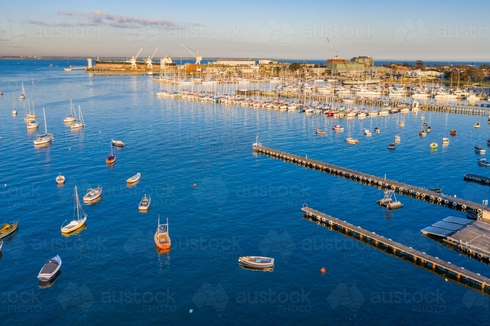 Aerial view a bay side yacht club with long jettys out over the water - Australian Stock Image