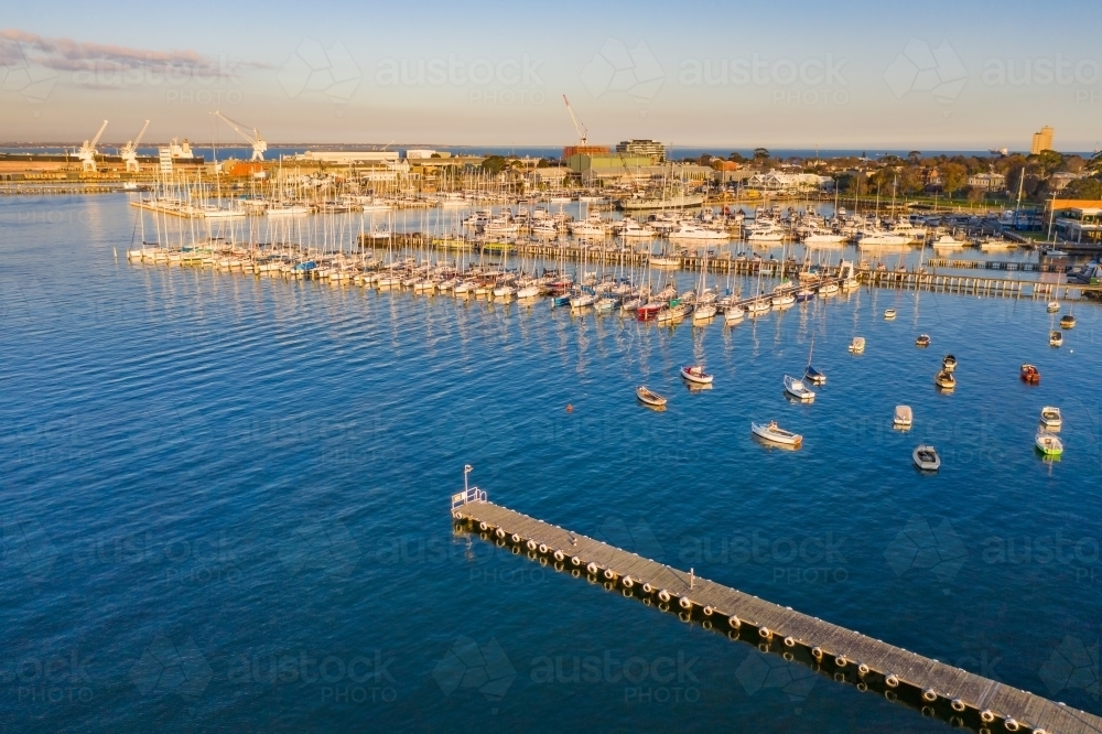 Aerial view a bay side yacht club with long jettys out over the water - Australian Stock Image