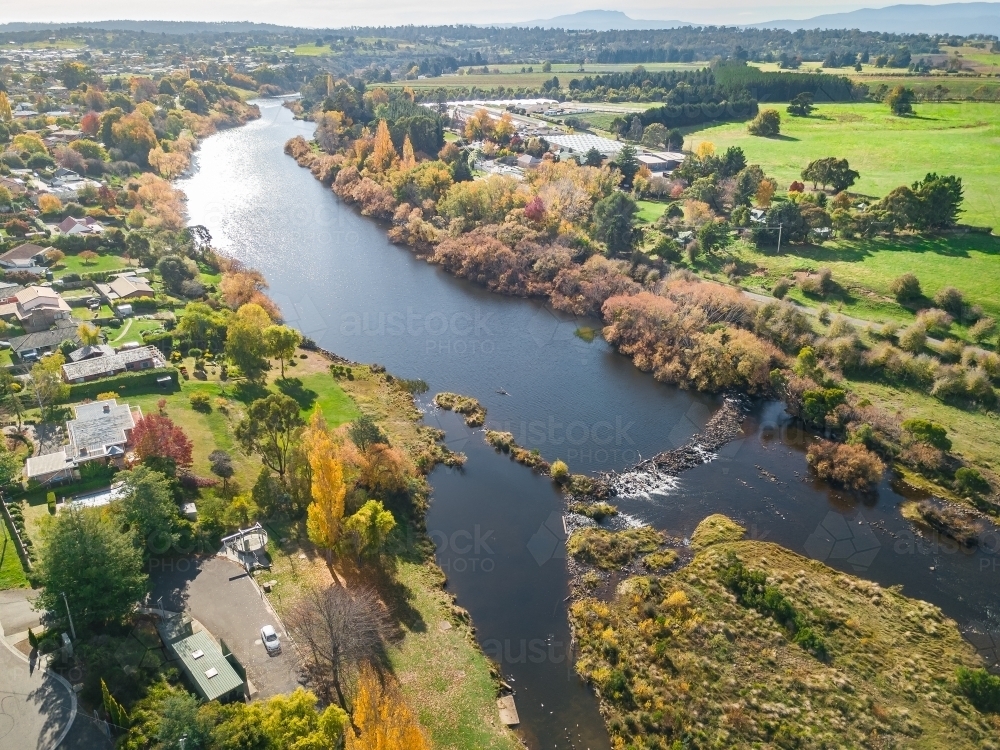 Aerial view a country town with golden autumn trees lining the riverbanks - Australian Stock Image