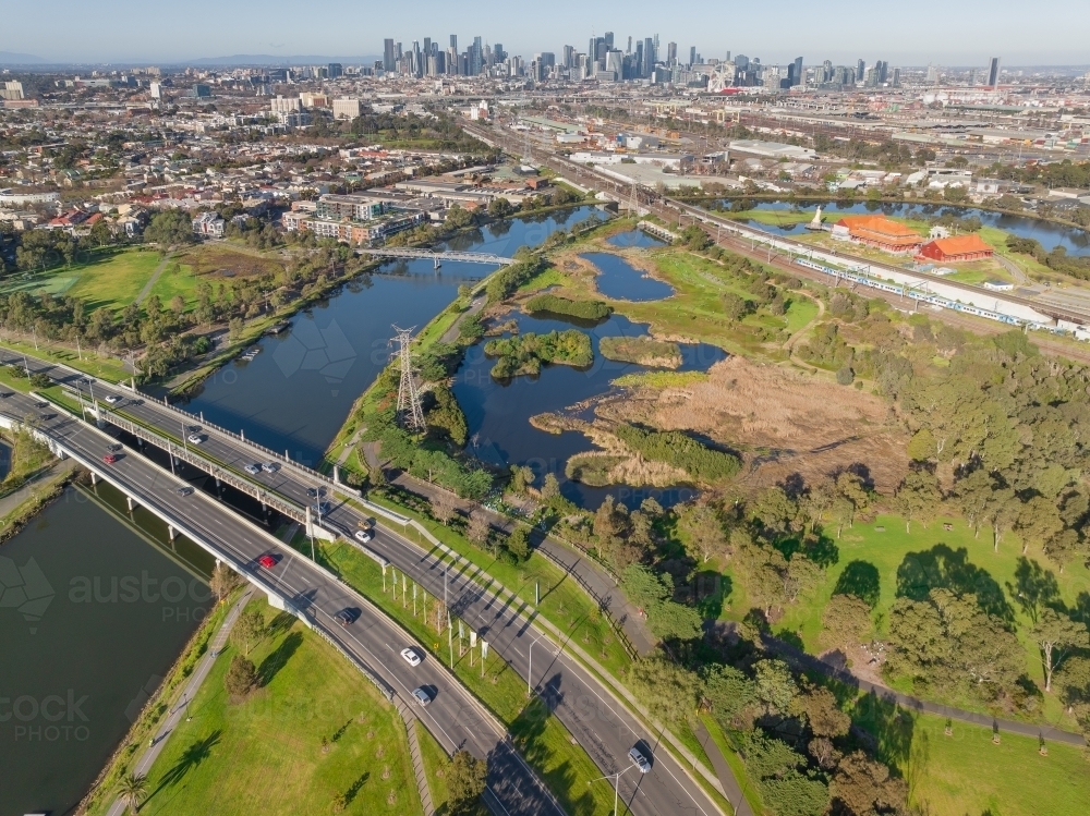 Aerial view a double lane bridge crossing an inner city river alongside green wetlands - Australian Stock Image
