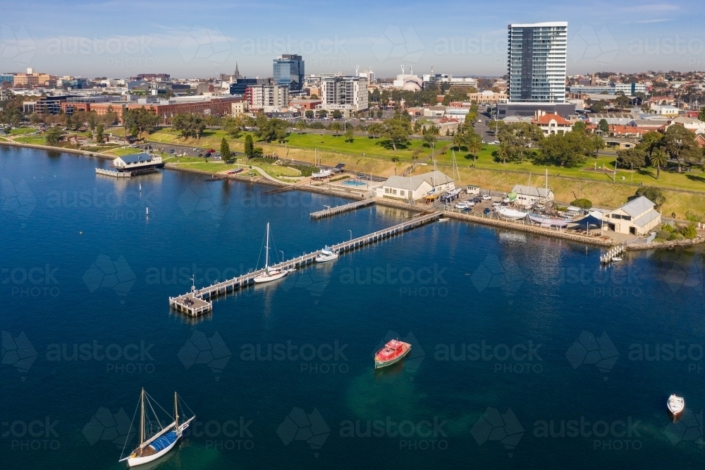 Aerial view along a city coastline with yachts and boats anchored at a jetty - Australian Stock Image