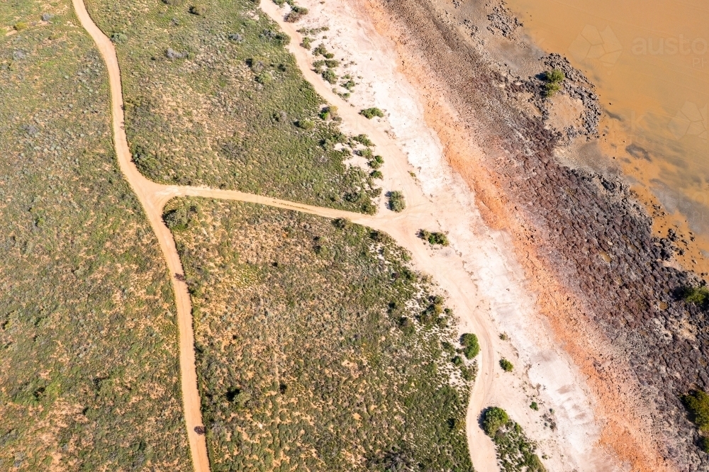 aerial view looking down on intertidal zone and beach with tracks through dunes - Australian Stock Image