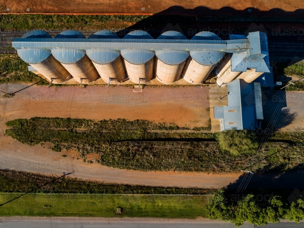 Aerial view looking down on rural silos in a row beside railway track in Riverina area - Australian Stock Image