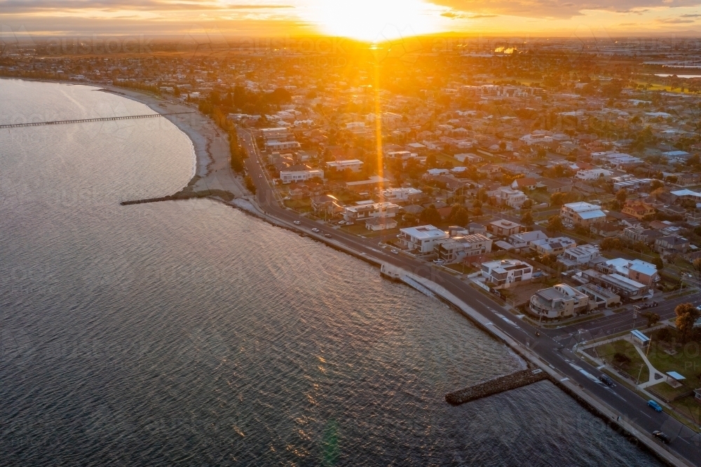 Aerial view of a bay side beach suburb and esplanade at sunset - Australian Stock Image