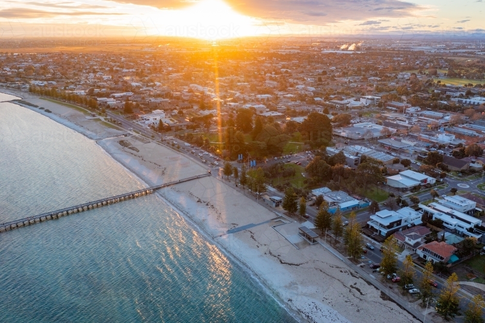 Aerial view of a bay side beach suburb and jetty at sunset - Australian Stock Image