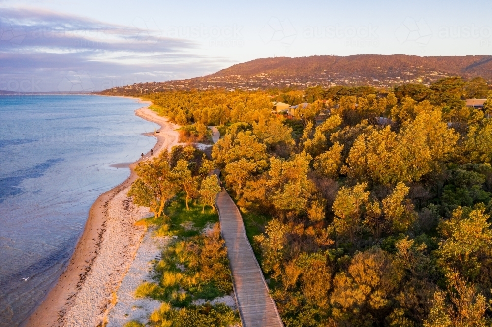 Aerial view of a board walk running  parallel to the beach at dusk - Australian Stock Image