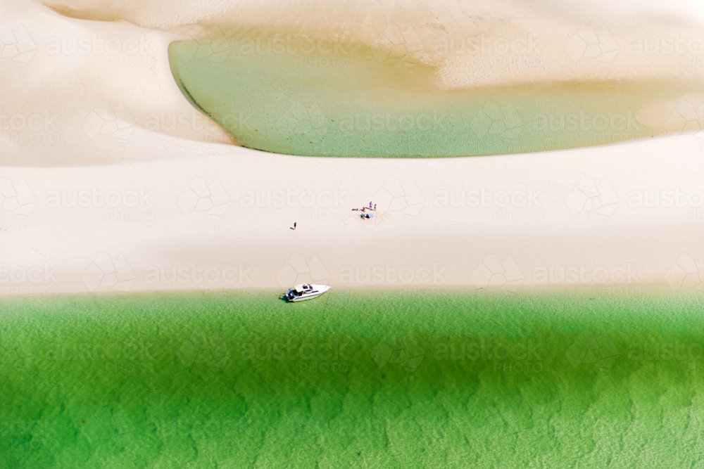 Aerial view of a boat anchored by a remote sandbar with vivid green shallows - Australian Stock Image
