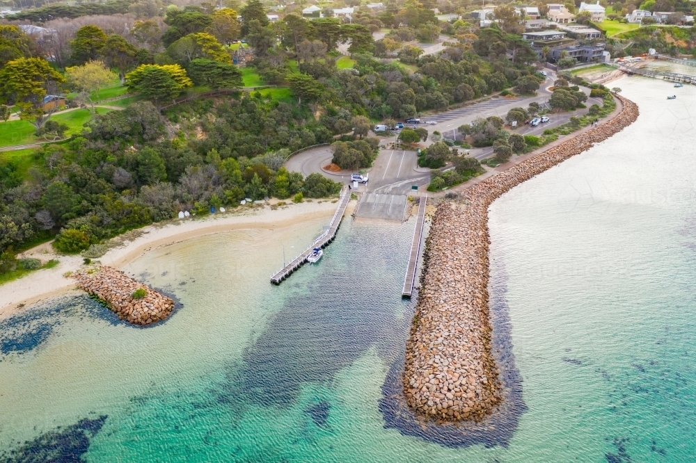 Aerial view of a boat ramp protected by a long rocky break water - Australian Stock Image