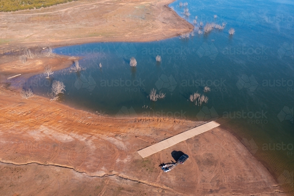 Aerial view of a car and trailer at a boat ramp on the shores of a lake - Australian Stock Image