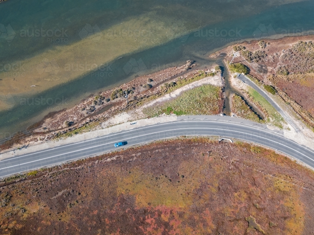 Aerial view of a car on a bend in the road along side a river - Australian Stock Image