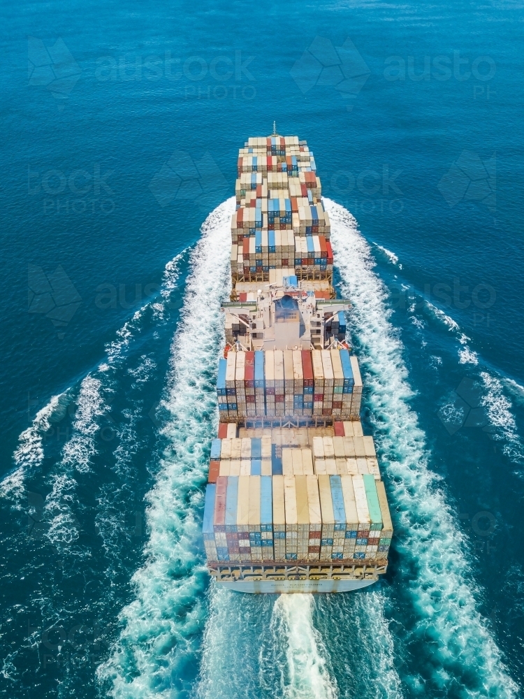 Aerial view of a cargo ship steaming through calm blue water - Australian Stock Image