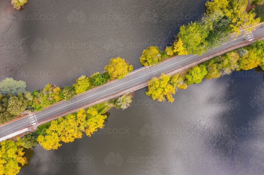 Aerial view of a causeway road lined with autumn trees - Australian Stock Image