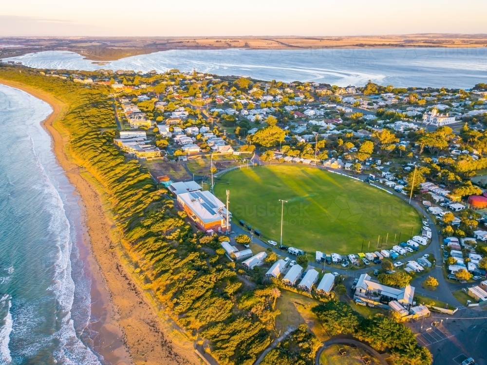 Aerial view of a coastal football oval surrounded by caravans and camp sites - Australian Stock Image