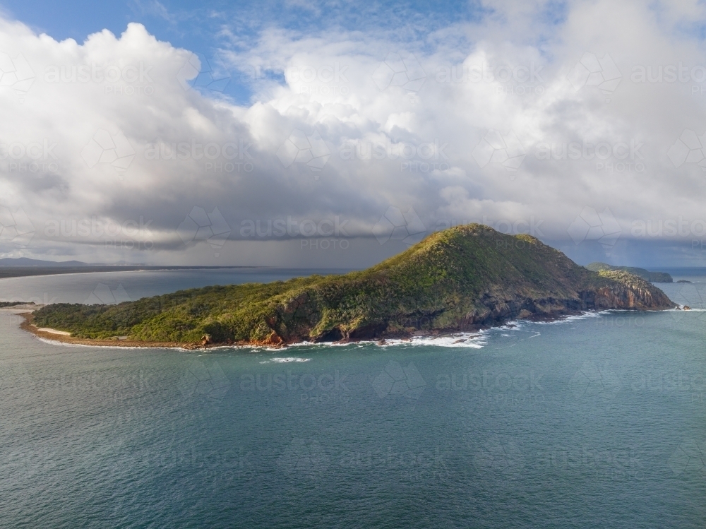 Aerial view of a coastal headland with dramatic clouds above - Australian Stock Image