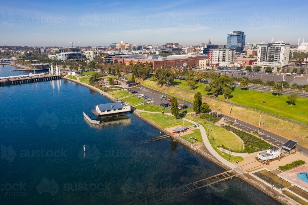 Aerial view of a coastal reserve with walking paths and boat sheds and a city in the back ground - Australian Stock Image