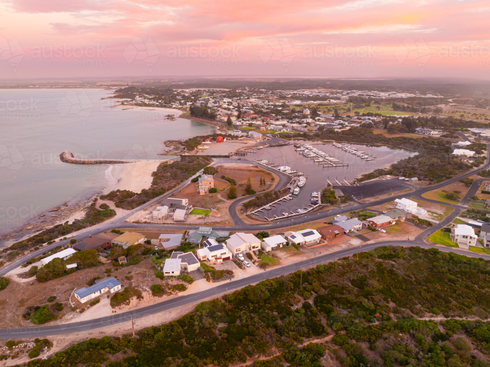 Aerial view of a coastal town and marina under a colourful twilight sky - Australian Stock Image