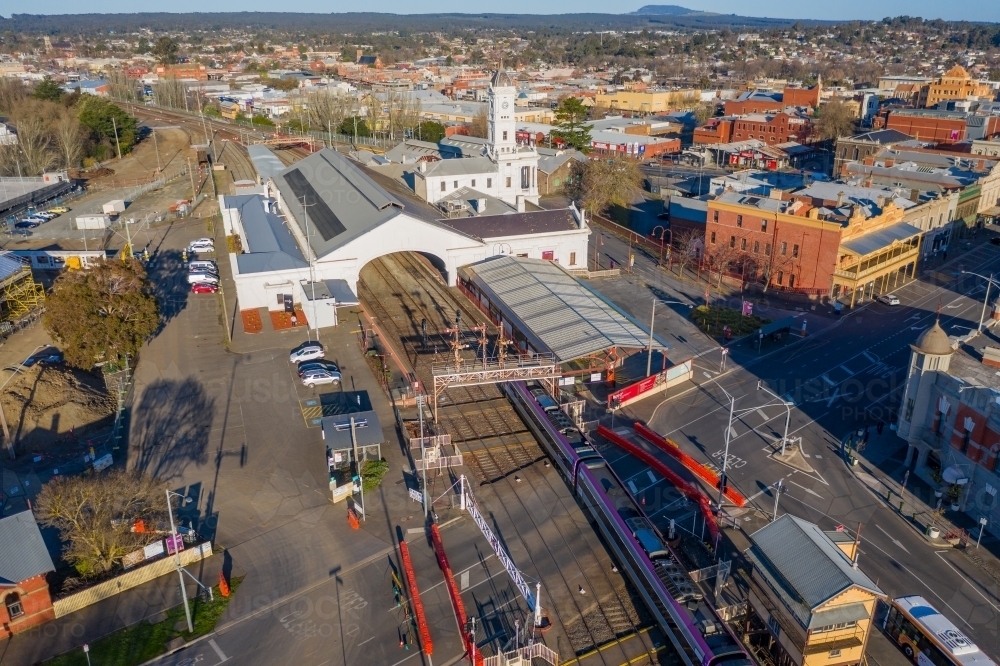 Aerial view of a commuter train arriving at an historic regional railway station and tracks - Australian Stock Image