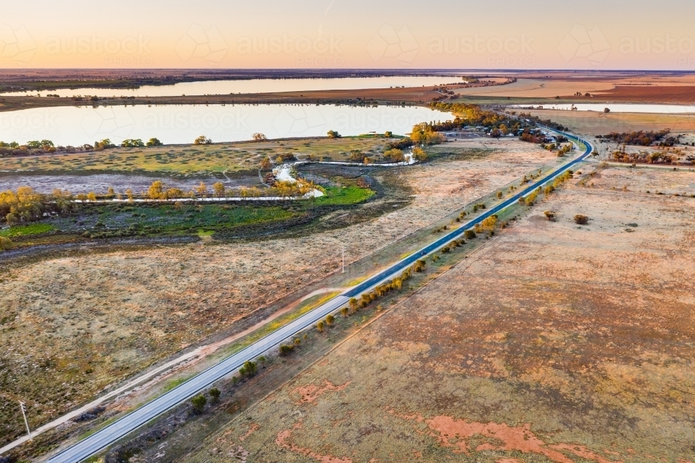 Aerial view of a country road and river heading towards an inland lake over dry farmland - Australian Stock Image