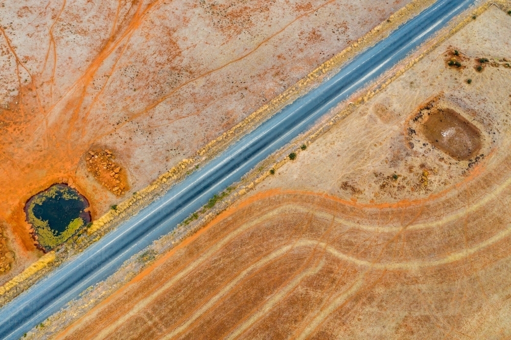 Aerial view of a country road next to a dam on dried farmland. - Australian Stock Image