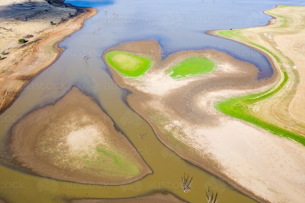 Aerial view of a dirty river winding around small islands with patches of grass - Australian Stock Image