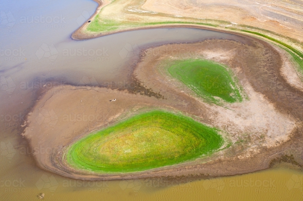 Aerial view of a dirty river winding around small islands with patches of grass - Australian Stock Image