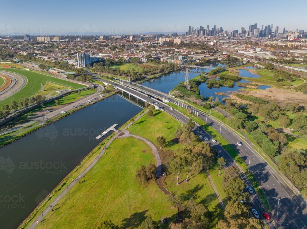 Aerial view of a double lane road crossing wide river in front of Melbourne city skyline - Australian Stock Image